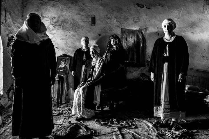 Five women inside an old abandoned local house, wearing the local costumes of Kardamyla, Chios
