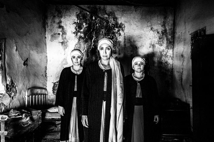 Three women wearing the local costumes of Kardamyla, standing in formation inside a local house