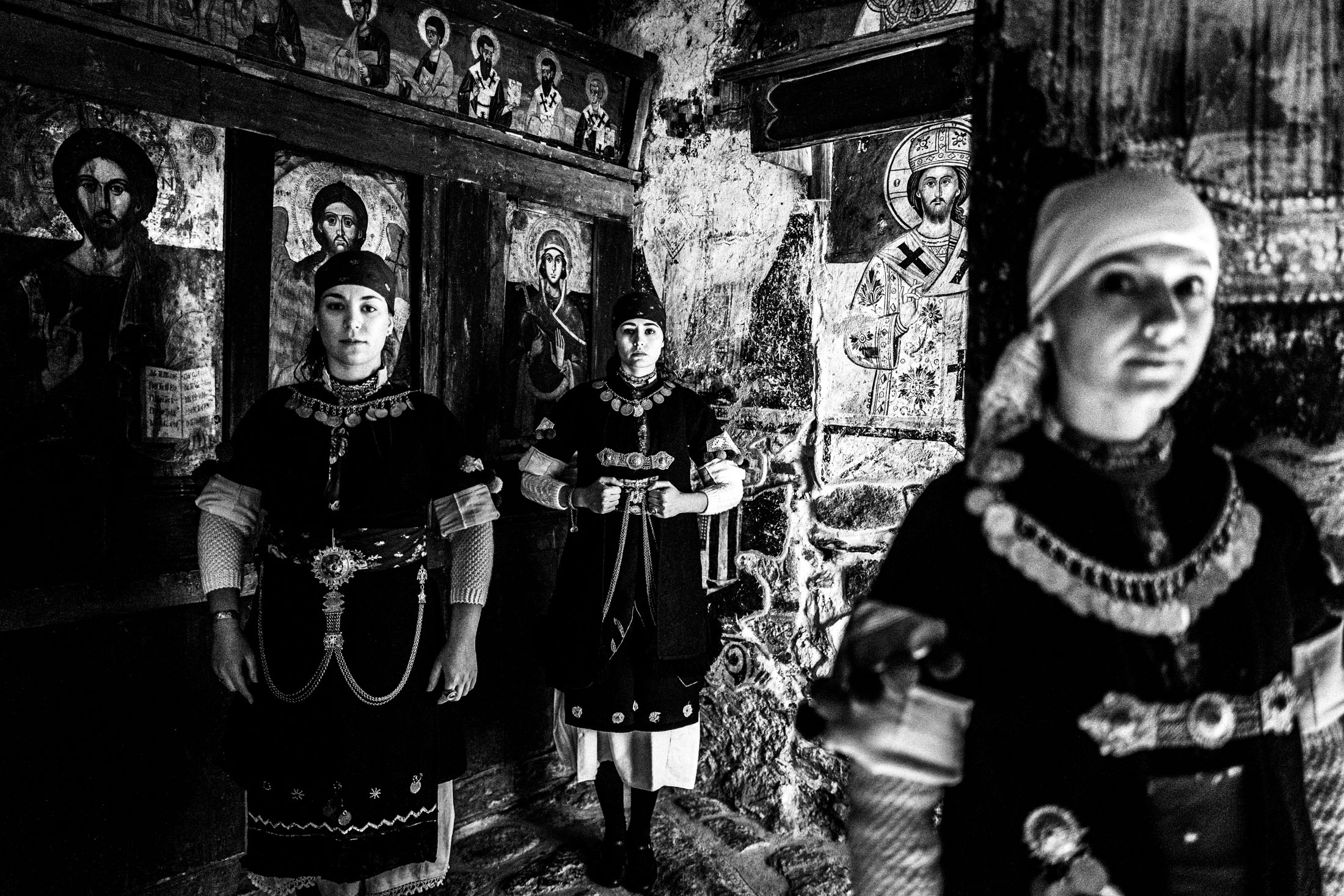Three women wearing the local costumes of Prespes, standing inside a local orthodox church