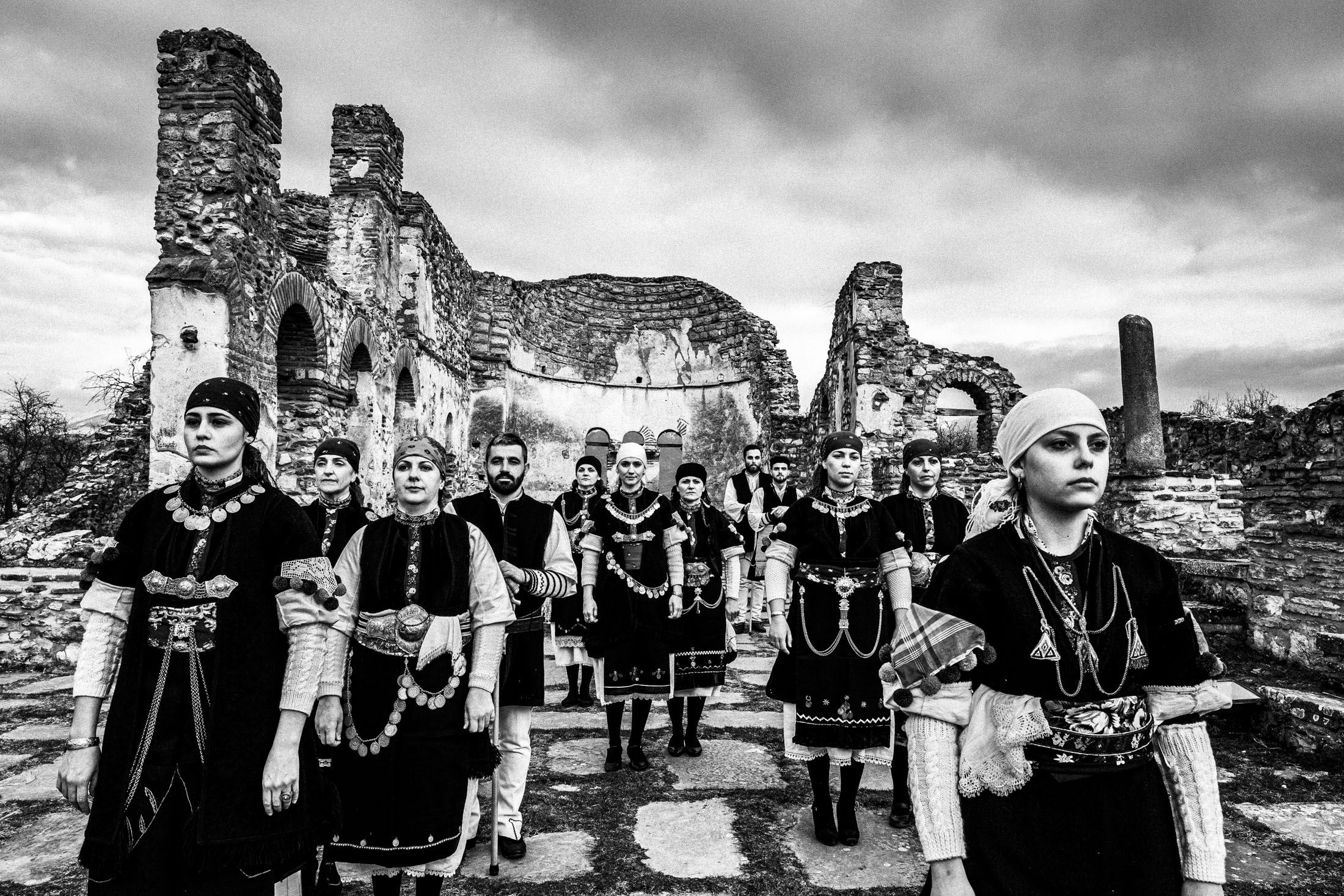 A group of people wearing the local costumes of Prespes in Florina, standing inside the ruins of the St. Achilles cathedral