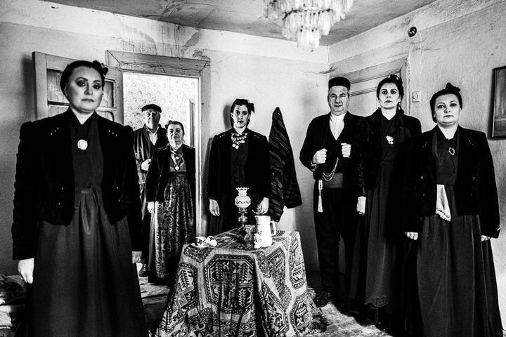 A group of people wearing the local costumes of Sohos, Thessaloniki standing inside a local house