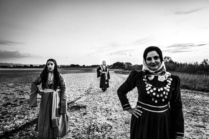 Three women in the traditional dresses of Kos, standing at the salt lake of Tigaki on the island.