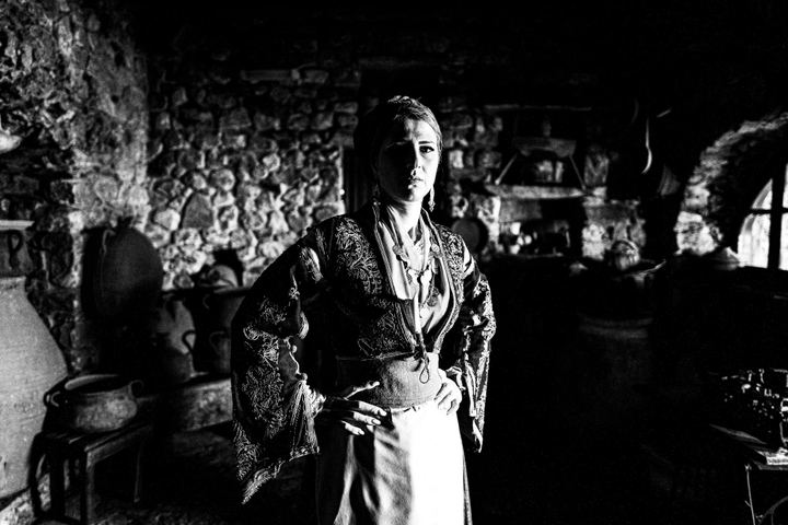 A woman wearing the local costume of Sfakia in Crete, inside a local warehouse