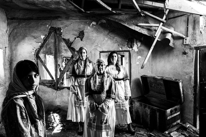 Women standing inside a ruined old abandoned local house in Volissos, Chios, wearing the local costumes