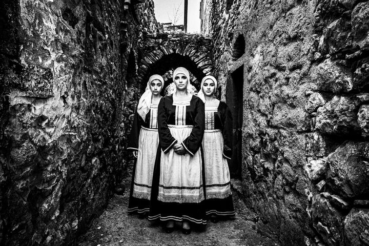 Three women standing in formation at the streets of Chalkio, Chios, wearing the local attire.