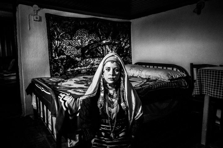 A woman wearing the traditional dress of Ormenio in Thrace, inside a local traditional bedroom. Evros, Thrace