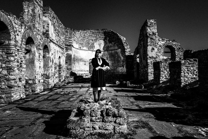 A woman standing inside the cathedral of St .Achillios of Prespes, wearing the local dress