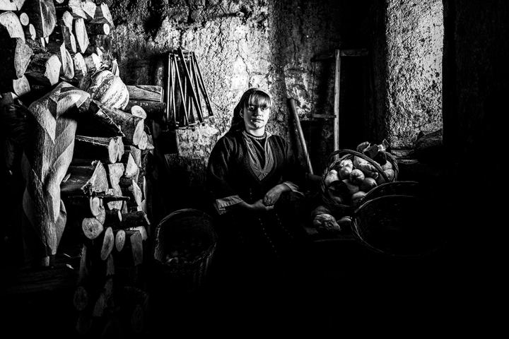 A young woman wearing the local costume of Prespes inside a local barn