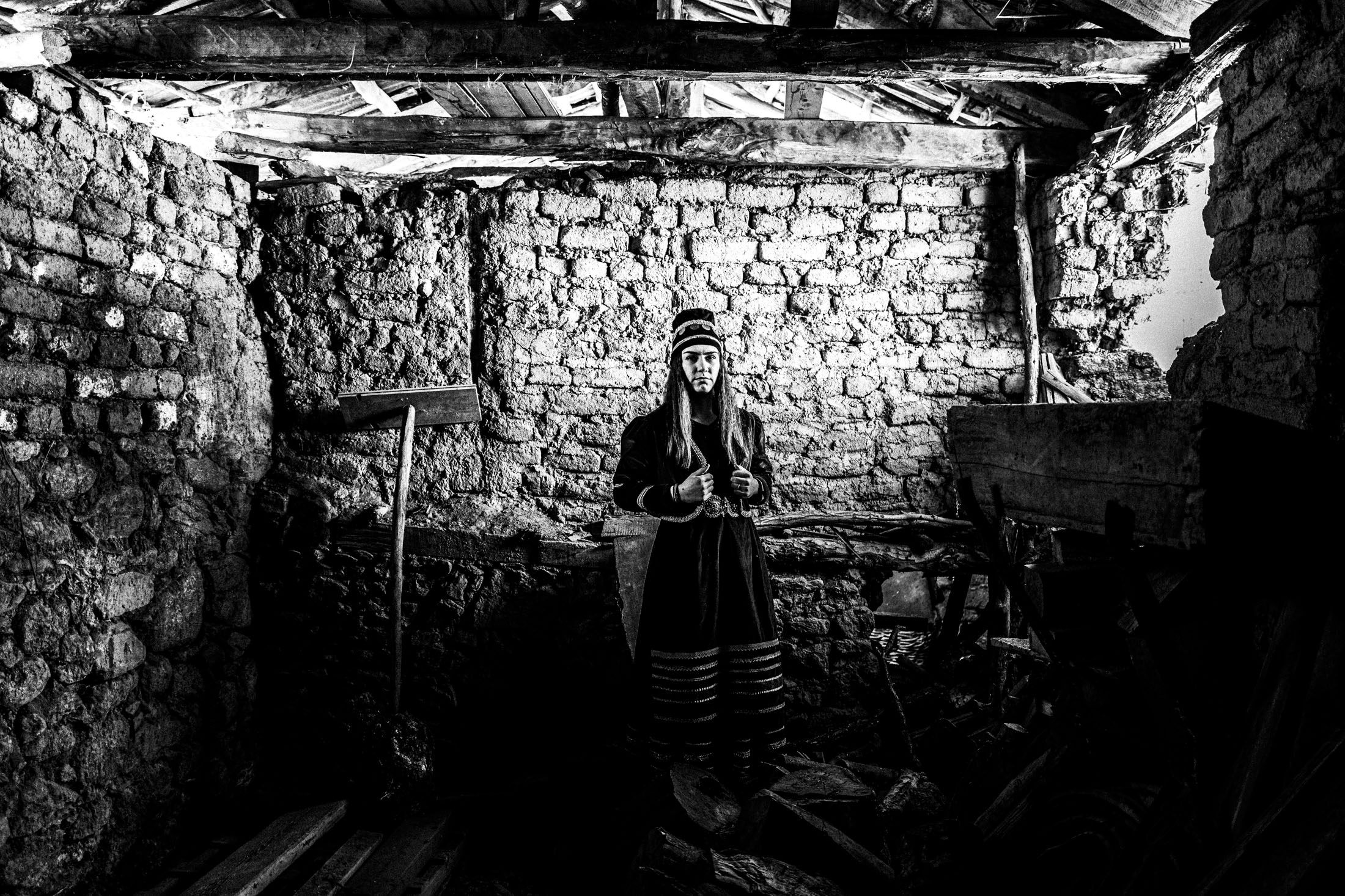 A young woman wearing the local costume of Prespes inside a local barn