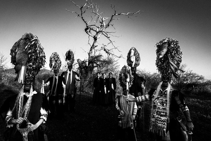 Bell bearers and women in traditional dress gathered in a winter field outside Sohos.