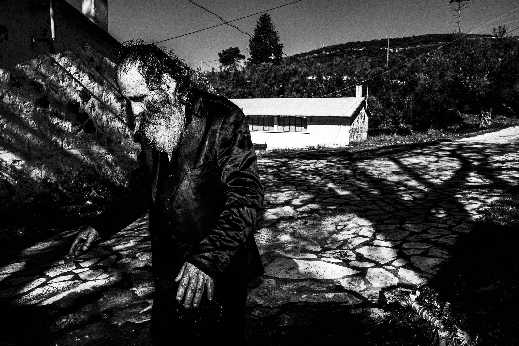 An exhausted older man walking outside the monastery in the morning.