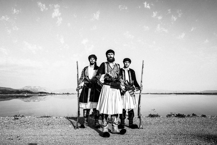 Three armed men in traditional Ntoulamas costume standing beside the lagoon.