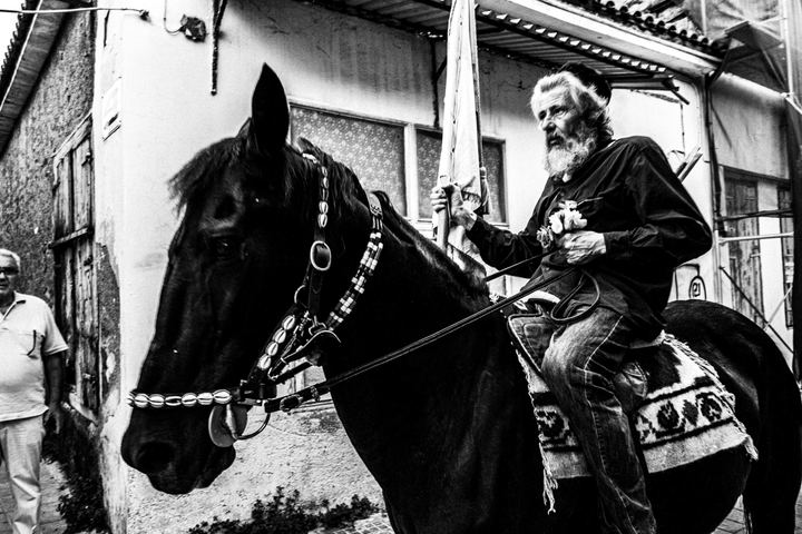 An older horse rider carrying a white flag through the streets of Messolonghi.