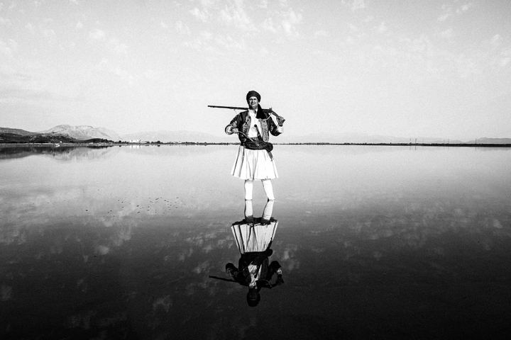 A man in traditional Ntoulamas standing alone beside the Messolonghi lagoon.