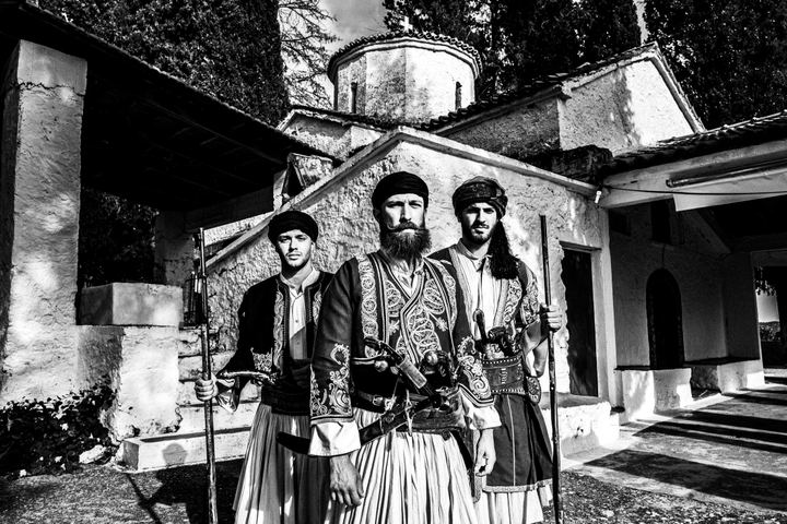 Three men in traditional armed costume standing in front of Saint Simeon church.