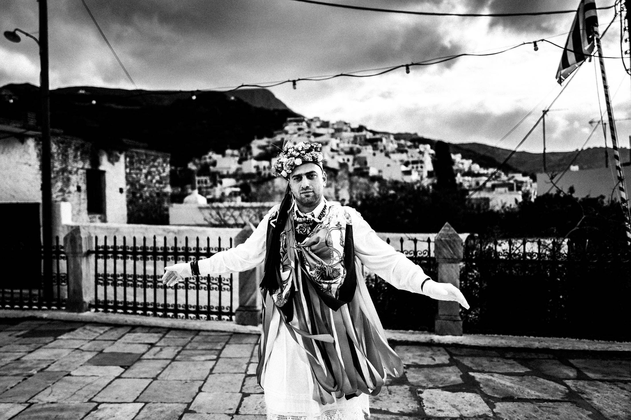 A ribboned Kordelatos dancing with open arms in the village of Filoti.