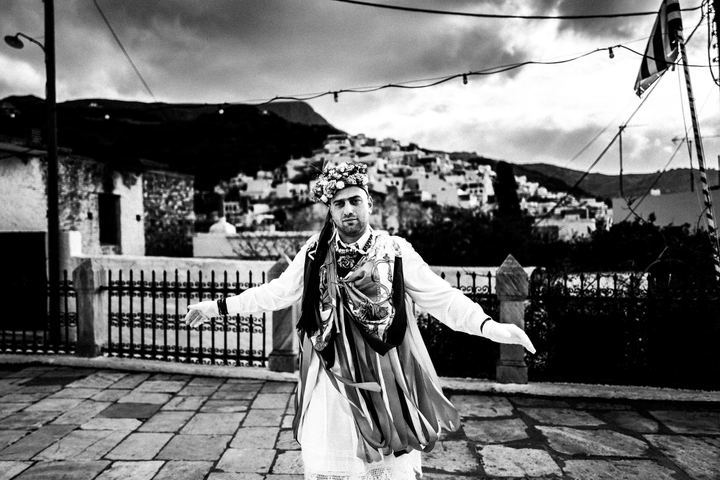 A ribboned Kordelatos dancing with open arms in the village of Filoti.