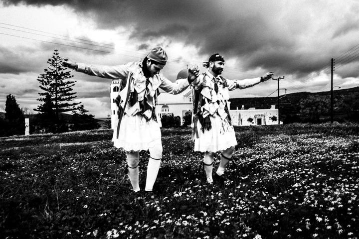Two Kordelatoi wearing fustanellas and ribbons in a field at Eggares.
