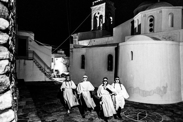 Masked torch bearers wearing white sheets during Lampadephoria in Naxos.