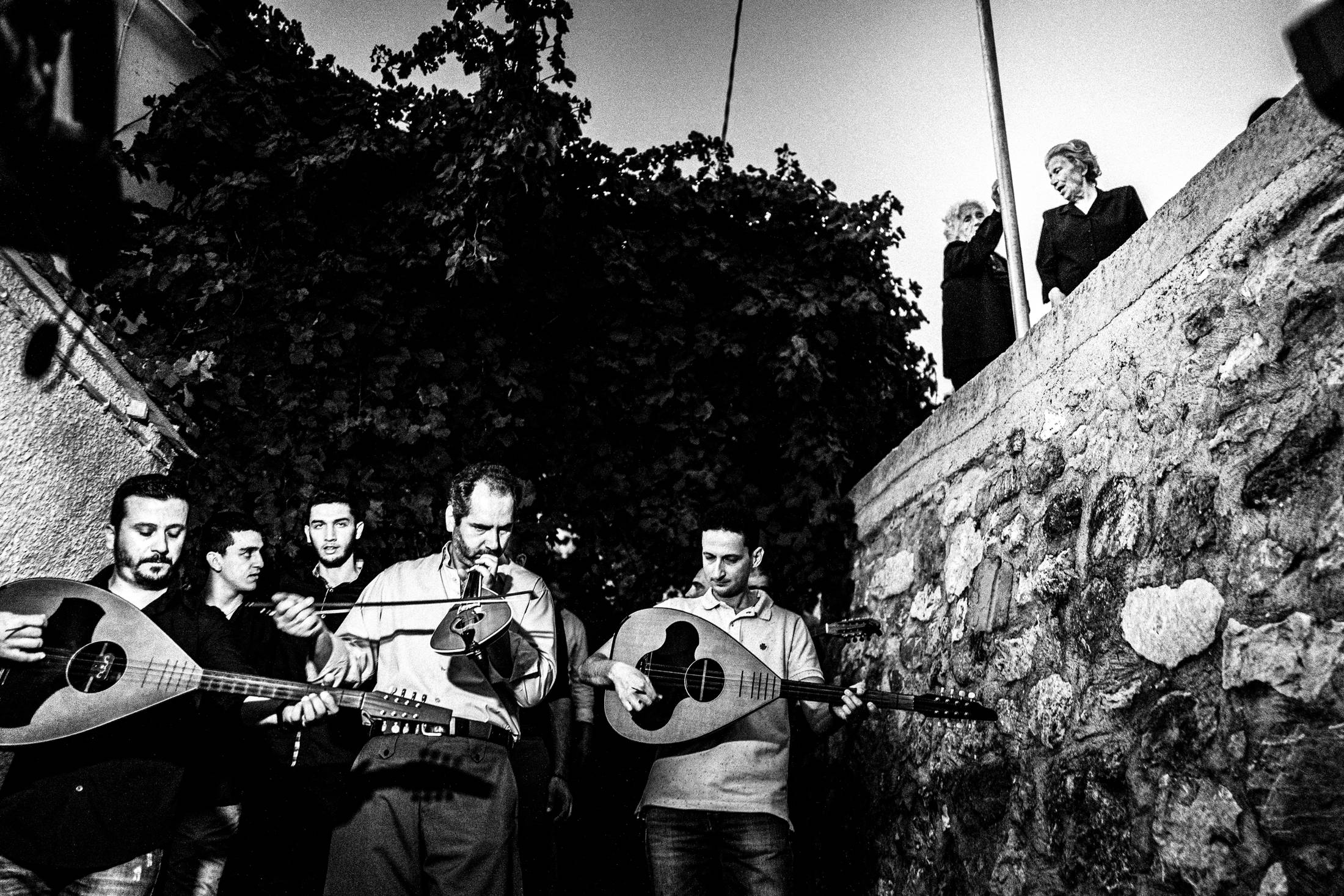 Musicians and villagers moving together through a street in Spili.