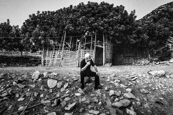 A man seated outside an improvised pilgrim hut at Panagia Charakiani.