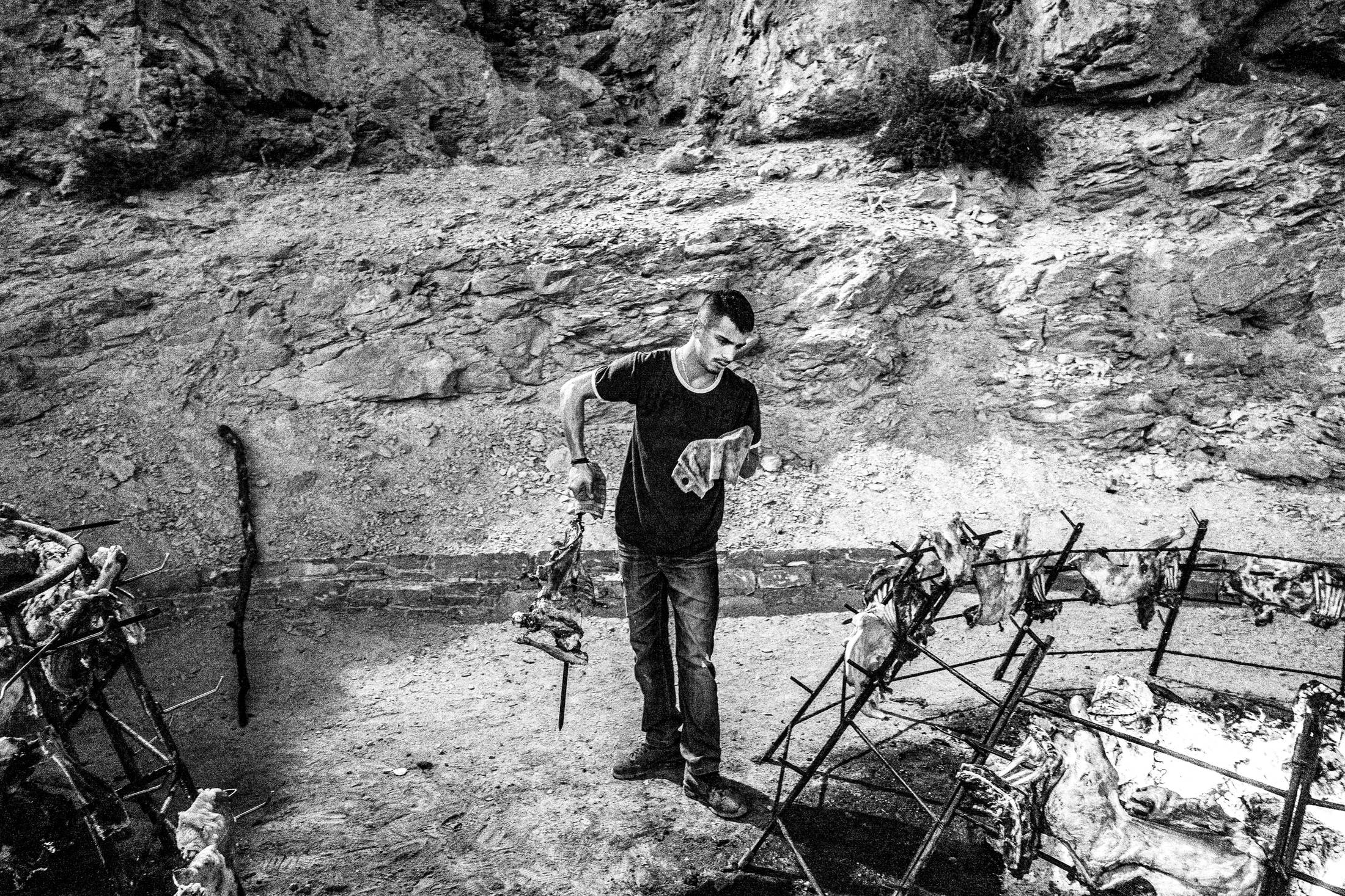 A man preparing lamb around an open fire on Psiloritis.