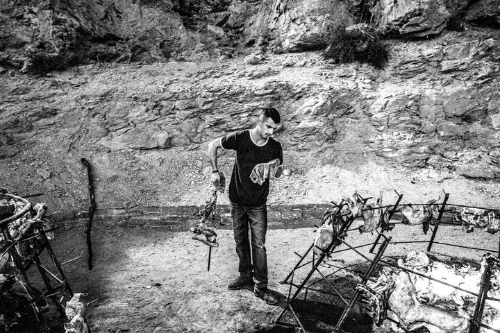 A man preparing lamb around an open fire on Psiloritis.