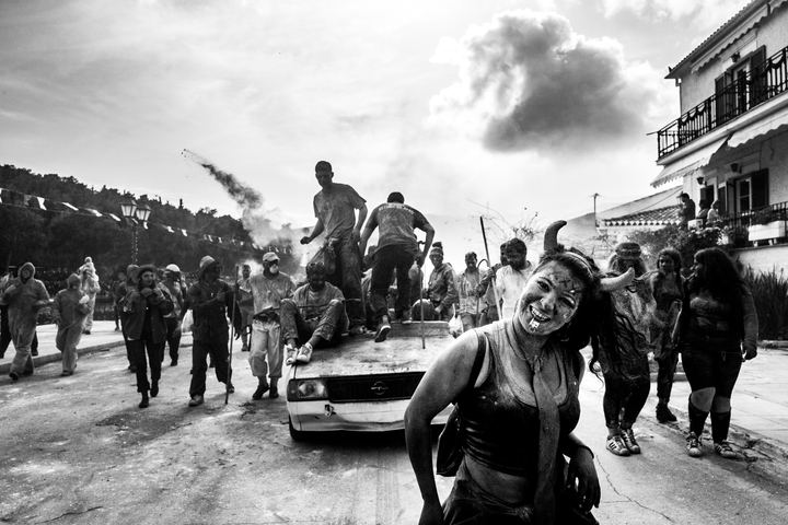 Flour-covered participants and an improvised vehicle moving towards the Galaxidi waterfront.