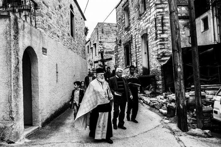 A priest leading the Good Friday procession along a narrow street in Patrika.