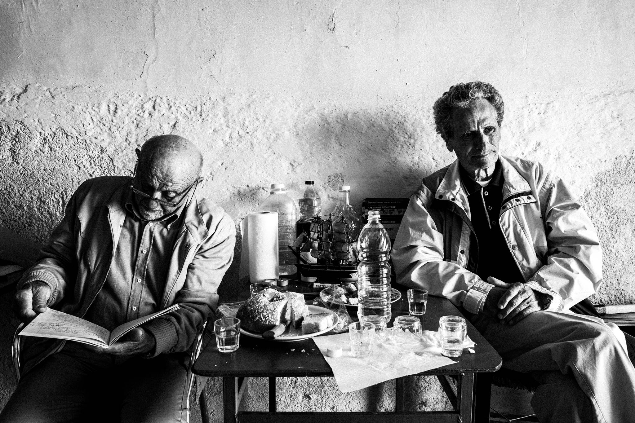 Two men sharing food and drinks inside a Kastellorizo home on Easter Sunday.