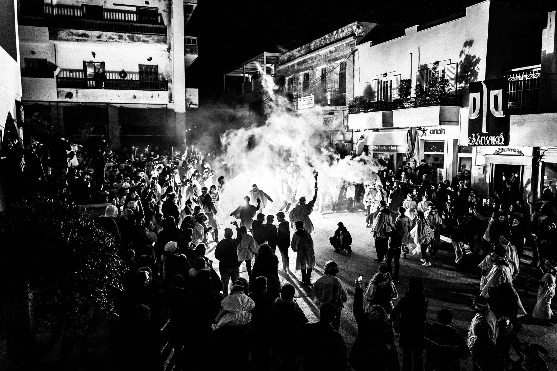 A large night crowd dancing around flames during Lampadephoria.
