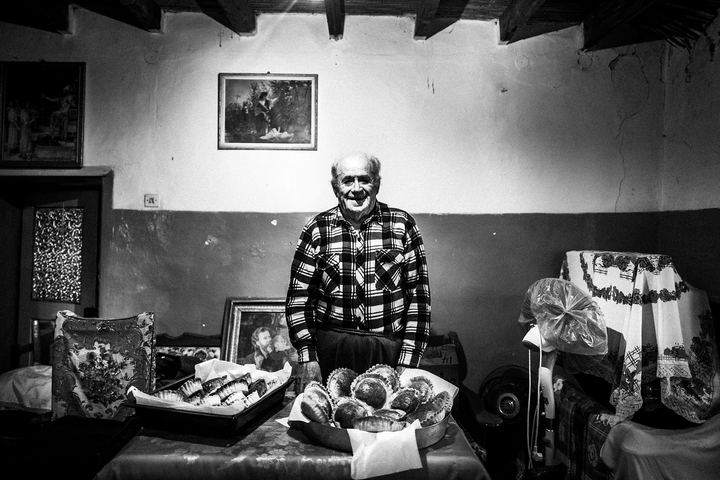 Black and white photograph of Sideris Gryllis standing behind trays of freshly baked Patiniotikes pies.