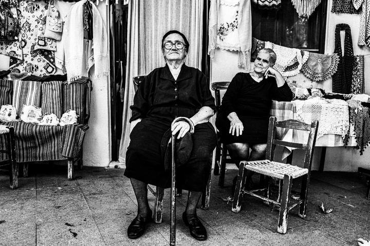 Black and white photograph of two friends at a local shop in Anogia, Crete.