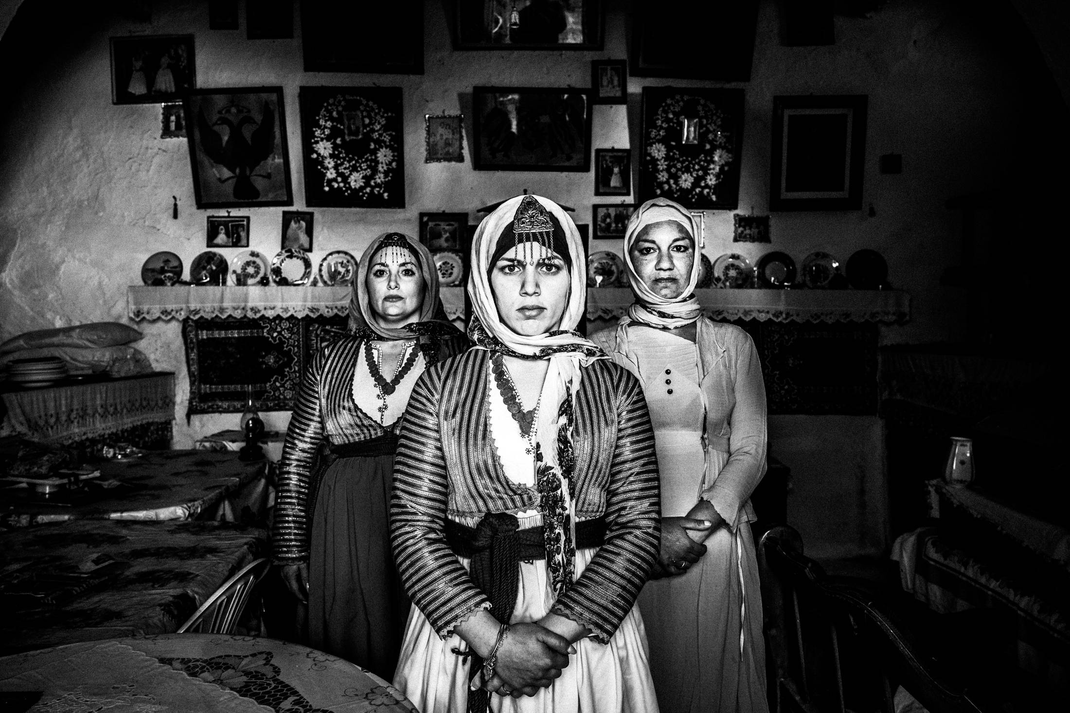 Three women wearing the costumes of Gennadi, Rhodes, stand inside a local house