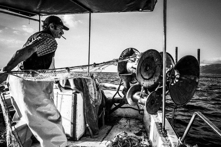 Black and white photograph of Yorgos pulling up a fishing net near Diafani, Karpathos.