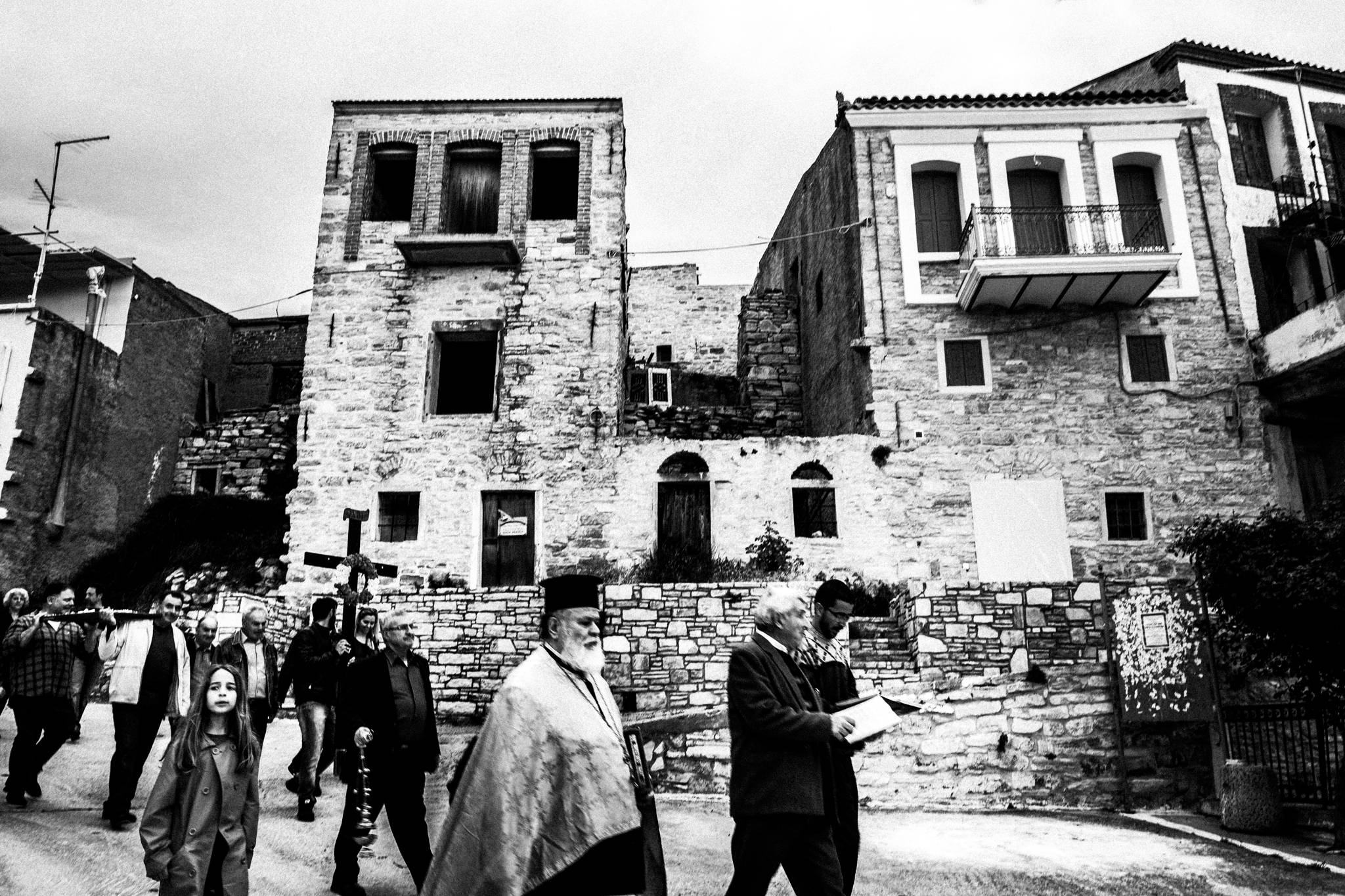 The Good Friday procession crossing an open section of Patrika beneath old stone buildings.