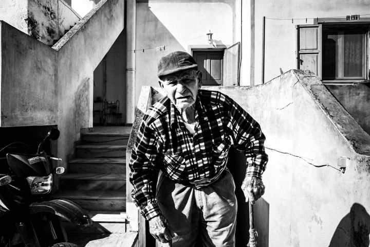 An elderly man facing the camera, outside his house in Emporio, Santorini