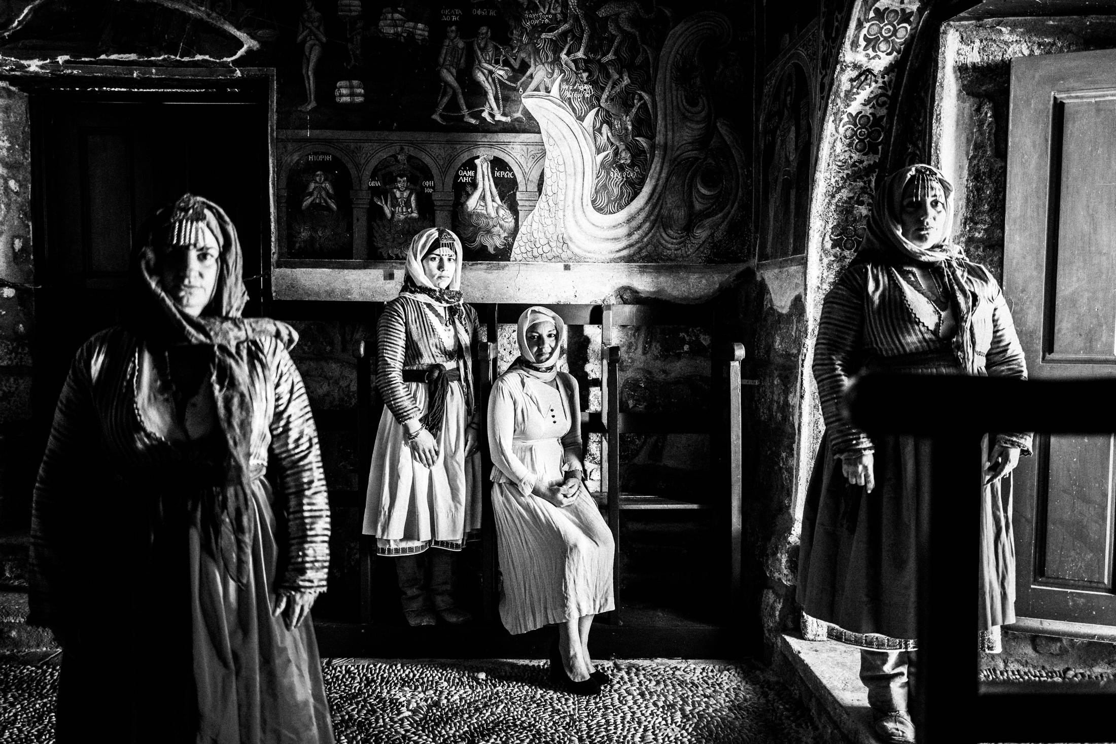 Four women wearing the costumes of Gennadi, Rhodes, inside a local church with side light