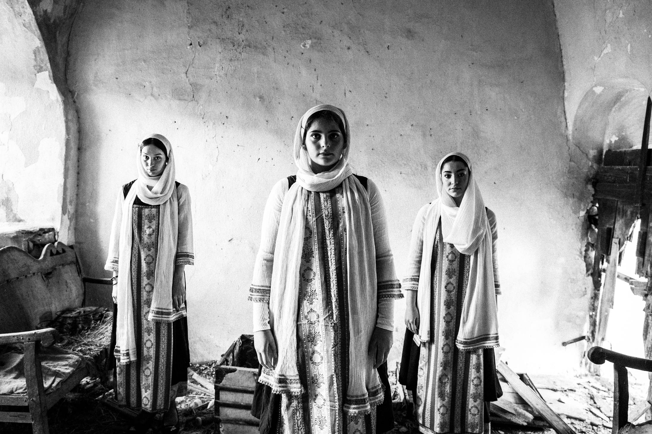 Women in the local dresses of Elata standing inside an old abandoned house