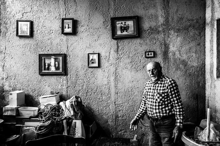 Black and white photograph of Stavros Choulis showing family photographs inside his house in Kastellorizo.