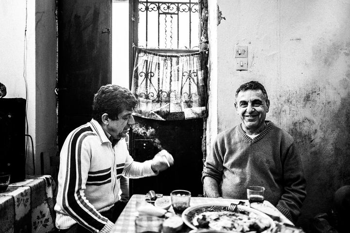 Black and white photograph of a man at the lunch table inside a family house in Ano Potamia, Naxos.