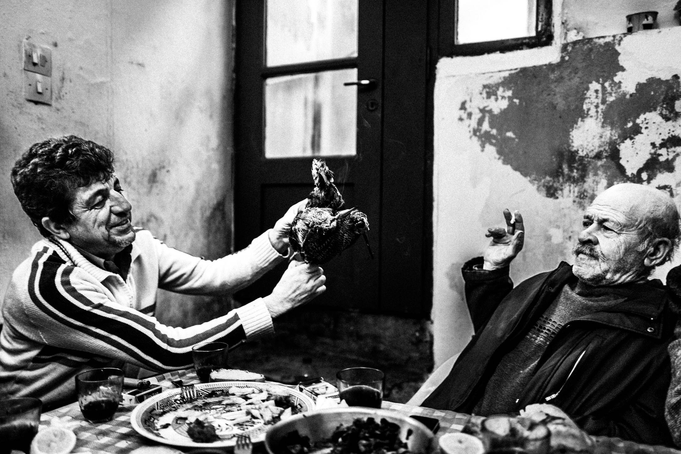 Black and white photograph of men eating lunch together in a local house in Ano Potamia, Naxos.