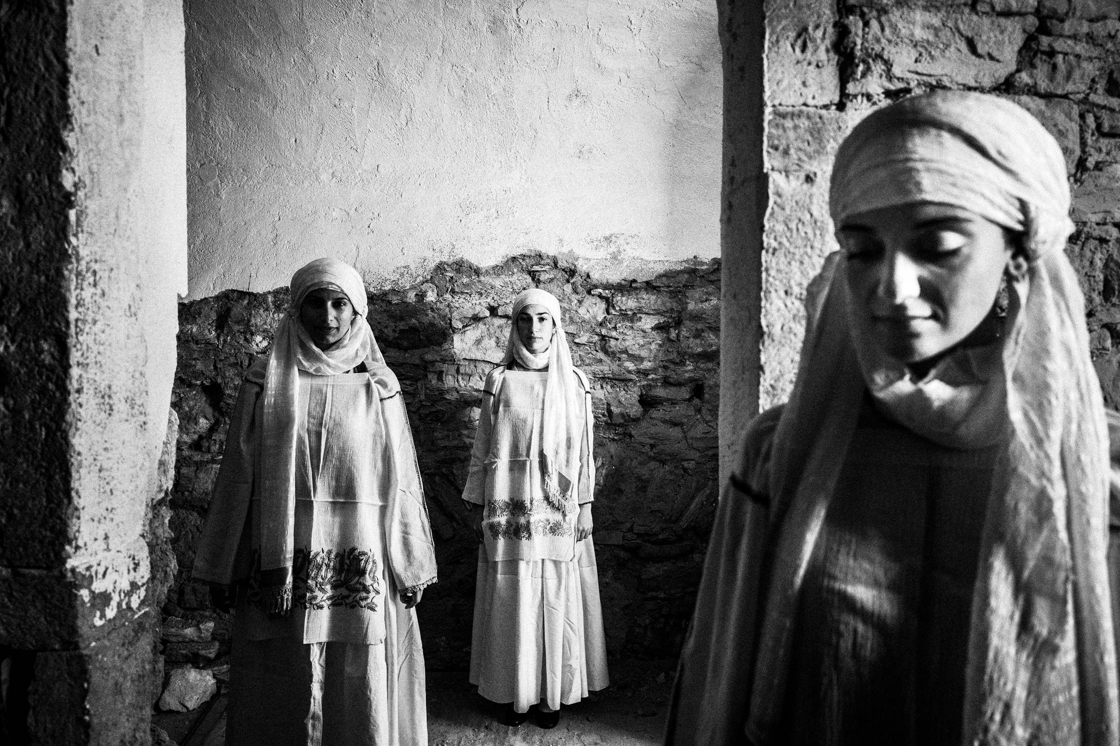 Three women wearing the local costumes of Kallimasia in Chios, inside an old abandoned local house.
