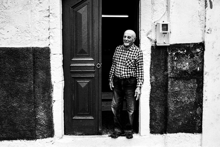 Black and white portrait of Stavros Choulis outside his home by the port of Kastellorizo.