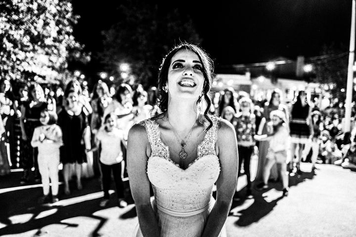 Black and white photograph of the bouquet toss after a wedding in Anogia, Crete.