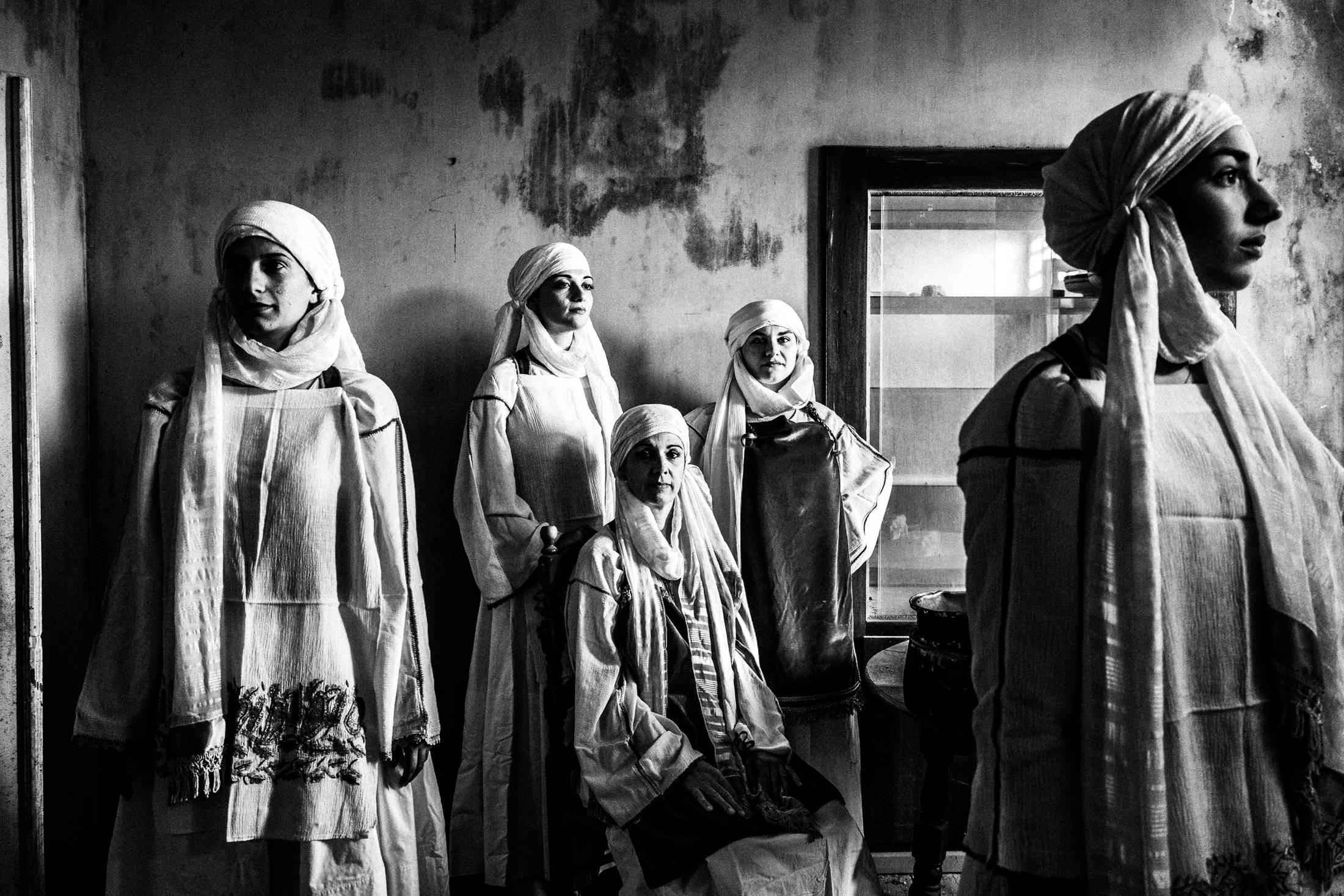 Three women wearing the local costumes of Kallimasia in Chios, inside an old abandoned local house.