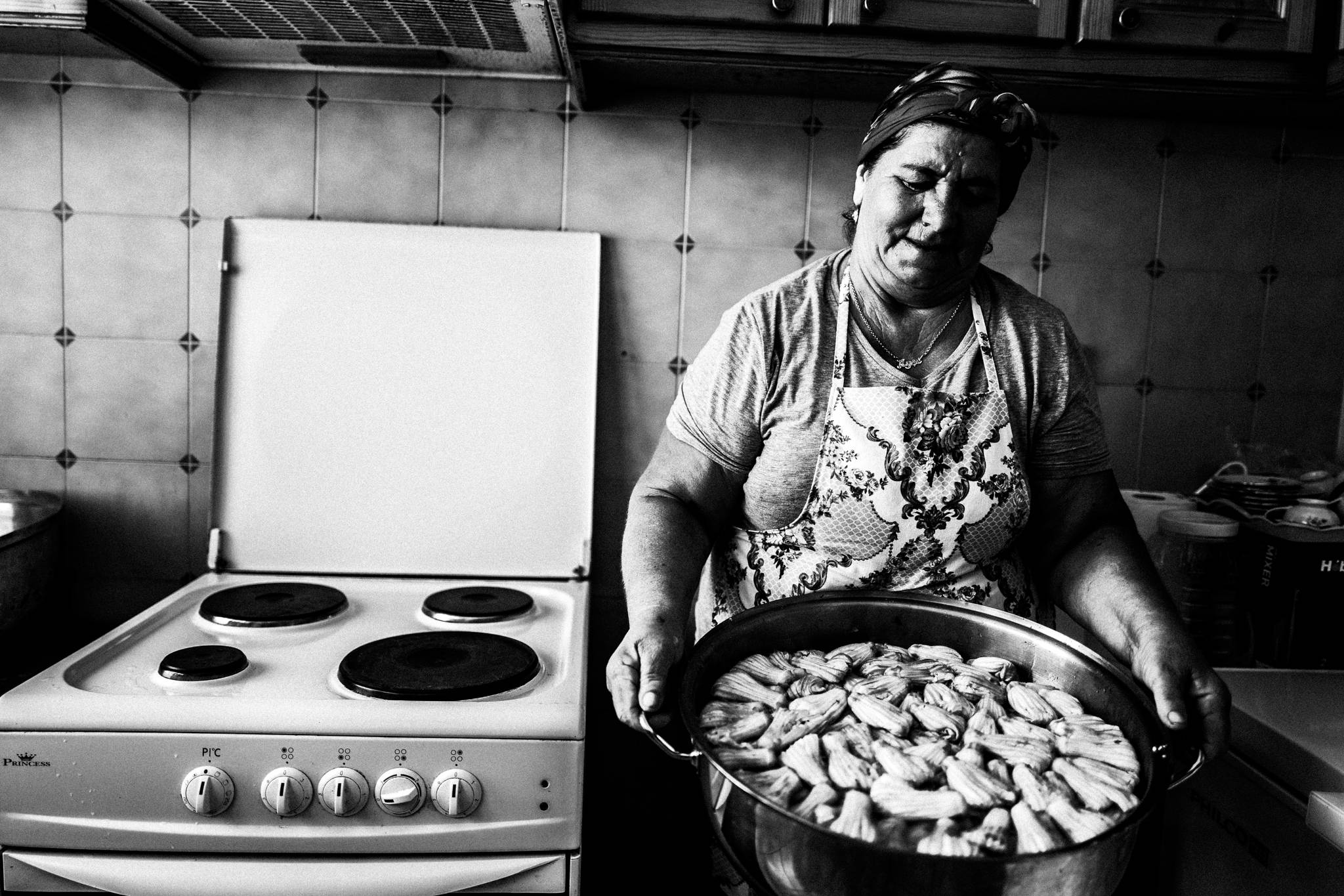 Ayshe holding a large tray of zucchini blossoms in her kitchen in Platani, Kos