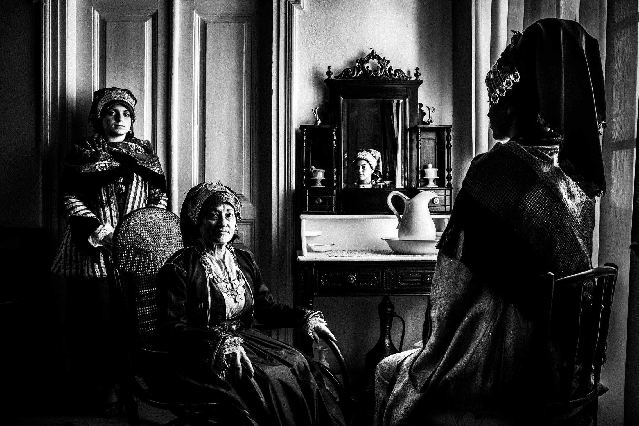 Three women wearing the local costumes of Symi, inside a local house