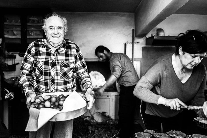 Black and white photograph of Sideris Gryllis holding dyed Easter eggs while Patiniotikes are prepared in the kitchen.