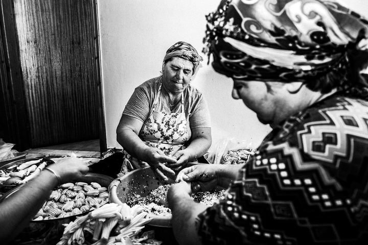 Women filling zucchini blossoms together around a table in a home in Platani, Kos